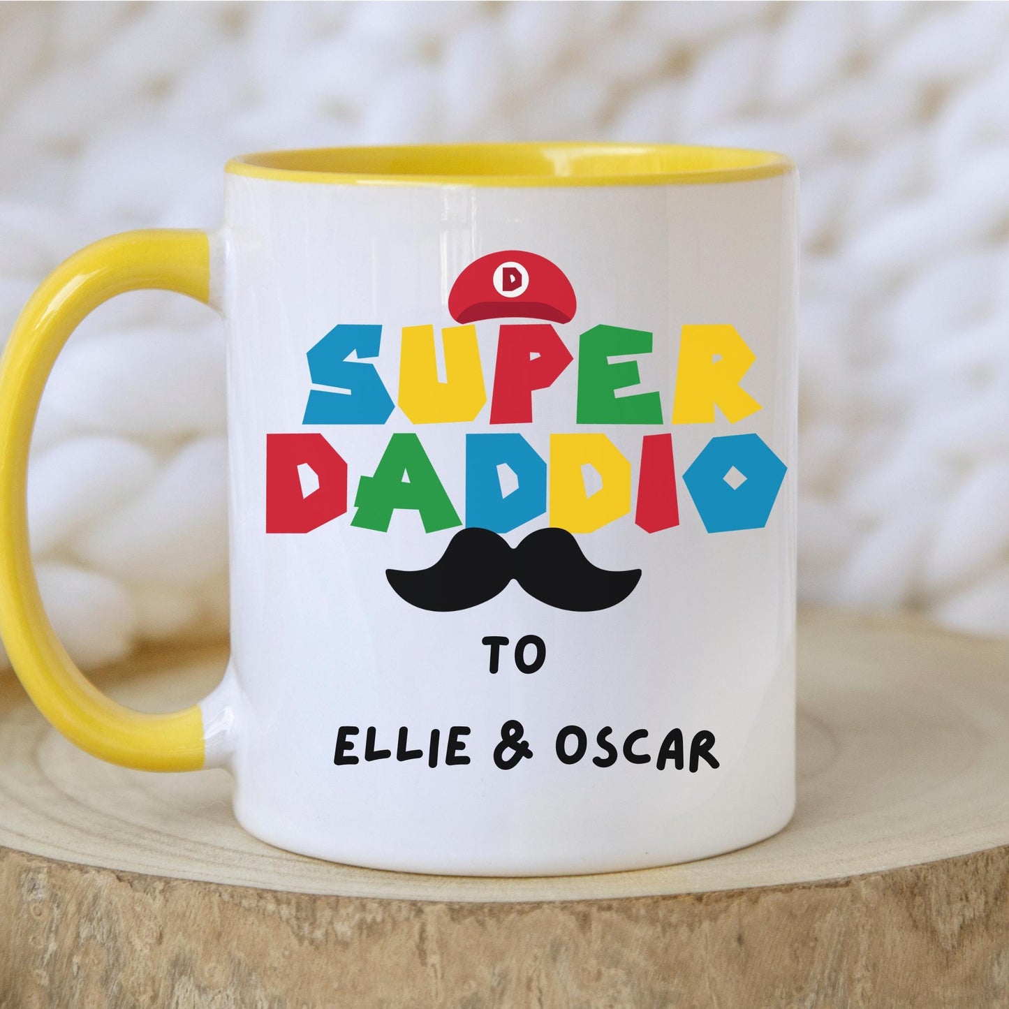 White ceramic coffee mug with colorful text reading 'Super Daddio', a red Mario-style hat, black moustache graphic, and personalised 'To Amber & Harry' message โ perfect custom Father's Day gift for gamer dads.