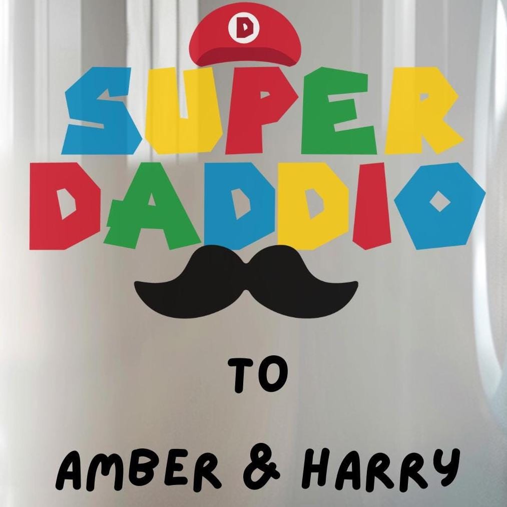 White ceramic coffee mug with colorful text reading 'Super Daddio', a red Mario-style hat, black moustache graphic, and personalised 'To Amber & Harry' message โ perfect custom Father's Day gift for gamer dads.