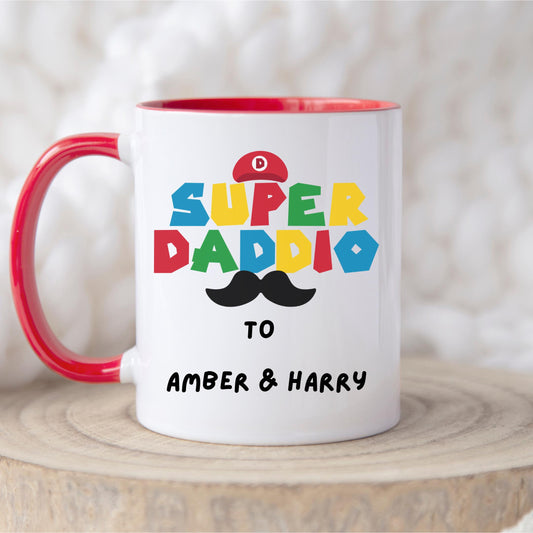White ceramic coffee mug with colorful text reading &#39;Super Daddio&#39;, a red Mario-style hat, black moustache graphic, and personalised &#39;To Amber & Harry&#39; message – perfect custom Father&#39;s Day gift for gamer dads.