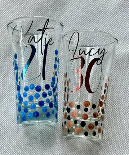 Personalised hand-painted birthday shot glasses with custom names and ages – 18th, 21st, 30th, and 50th designs in pink, blue, copper, and purple dot patterns – unique milestone party gift idea